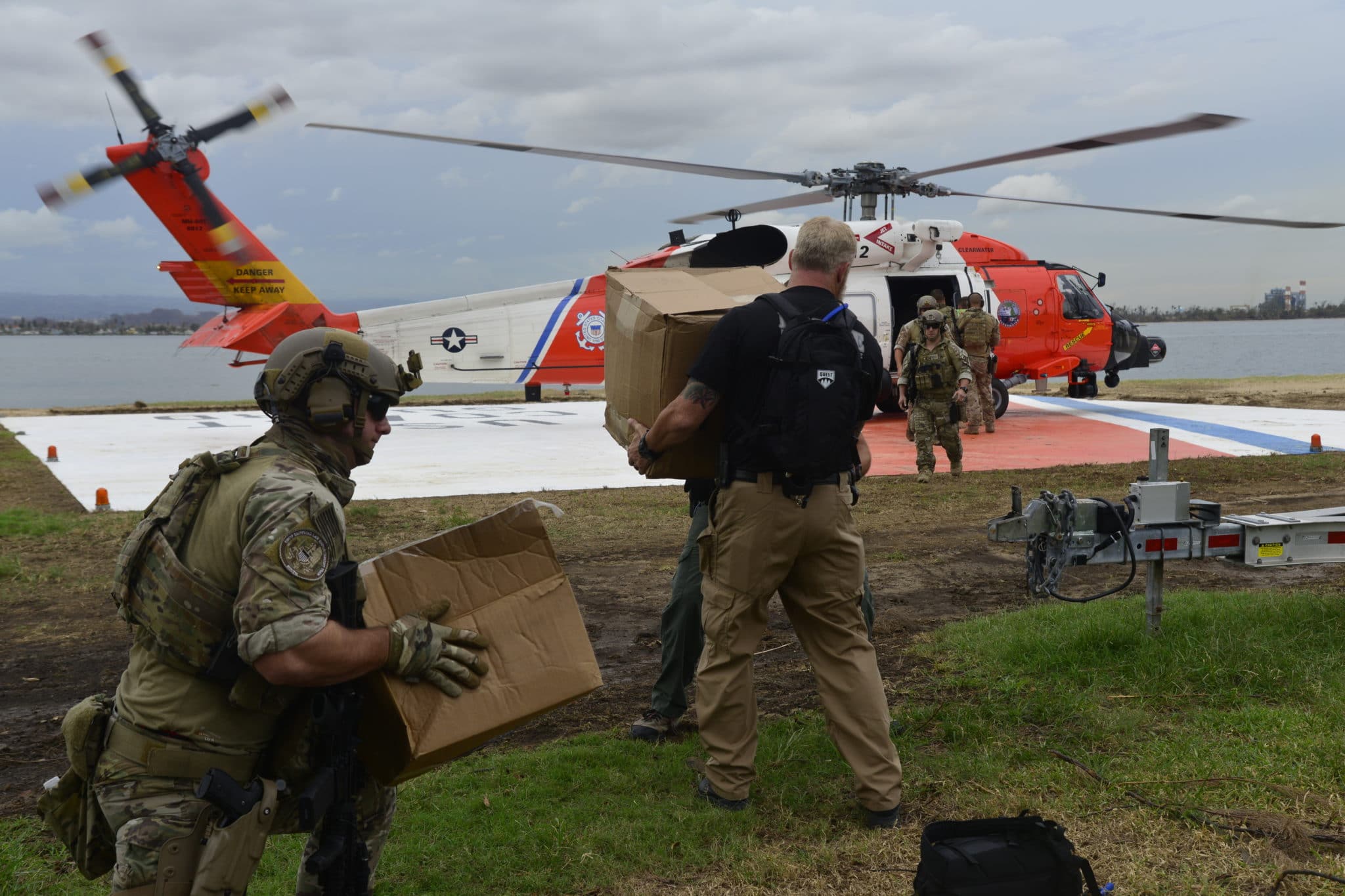 crewmembers load a Coast Guard MH-60 Jayhawk helicopter from Air Station Clearwater, Florida, with food and water