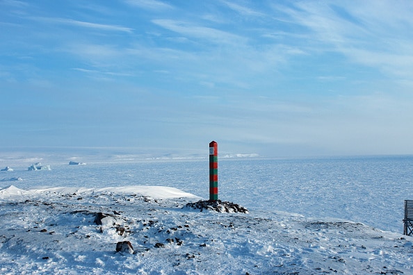 The state seal of the Russian Federation sits on top of a red and green post marking the Arctic border of the Russian Federation beside the Barents Sea on Alexandra Island in the Franz Josef Land archipelago, Russia, on Wednesday, March 29, 2017. Instead of waiting for global shippers to make a port of call, Russia is domesticating the transpolar conduit that could slash up to 12 days of travel time between Europe and Asia when its open four-and-a-half months each year. Photographer: Anna Andrianova/Bloomberg via Getty Images
